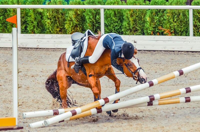 Young rider falling from horse during a competition. Horse show jumping accident.