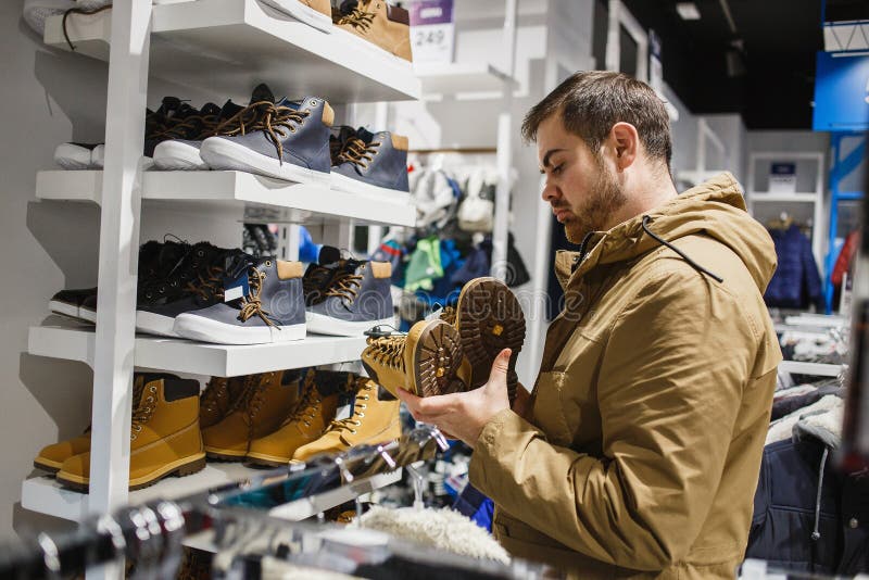 Equipaggi i pantaloni a vita bassa in rivestimento beige che sceglie gli stivali gialli dell'inverno in deposito - acquisto, modo fotografia stock libera da diritti Equipaggi i pantaloni a vita bassa in rivestimento beige che sceglie gli stivali gialli dell'inverno in deposito - acquisto, modo fotografia stock libera da diritti