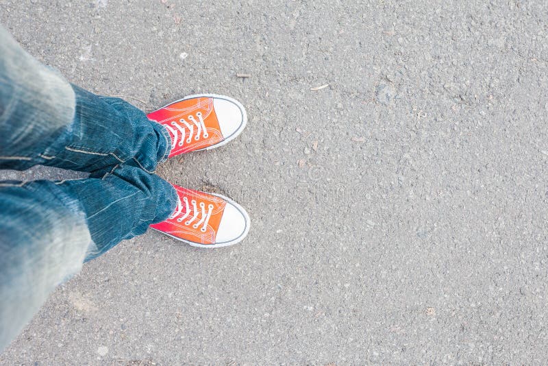 Equipaggi i piedi in scarpe da tennis rosse sulla strada cobbled
