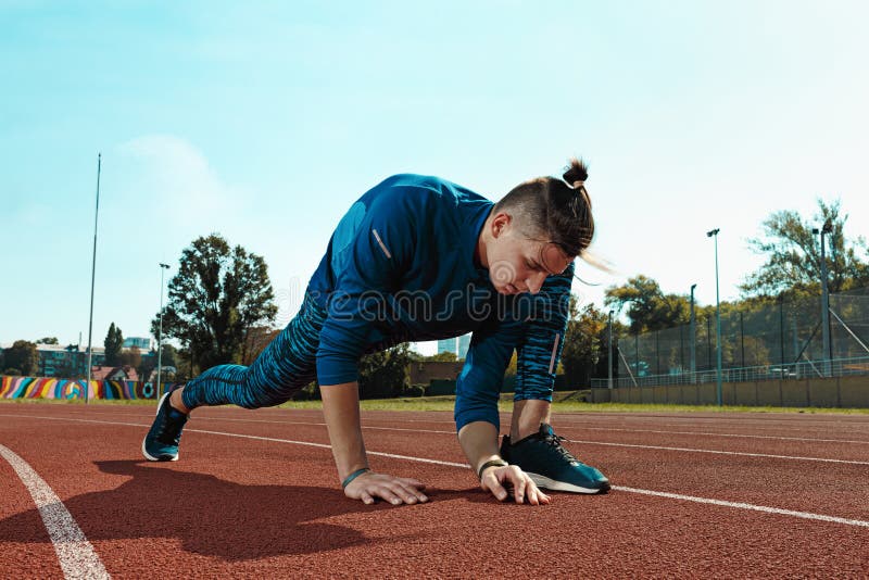 Equipaggi il corridore che allunga le gambe che preparano per l'addestramento di funzionamento sulle piste dello stadio che fanno fotografia stock Equipaggi il corridore che allunga le gambe che preparano per l'addestramento di funzionamento sulle piste dello stadio che fanno fotografia stock