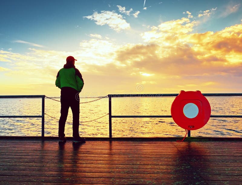 Equipaggi il supporto al corrimano sulla talpa ed il mare esaminare all'orizzonte di mattina immagini stock libere da diritti Equipaggi il supporto al corrimano sulla talpa ed il mare esaminare all'orizzonte di mattina immagini stock libere da diritti