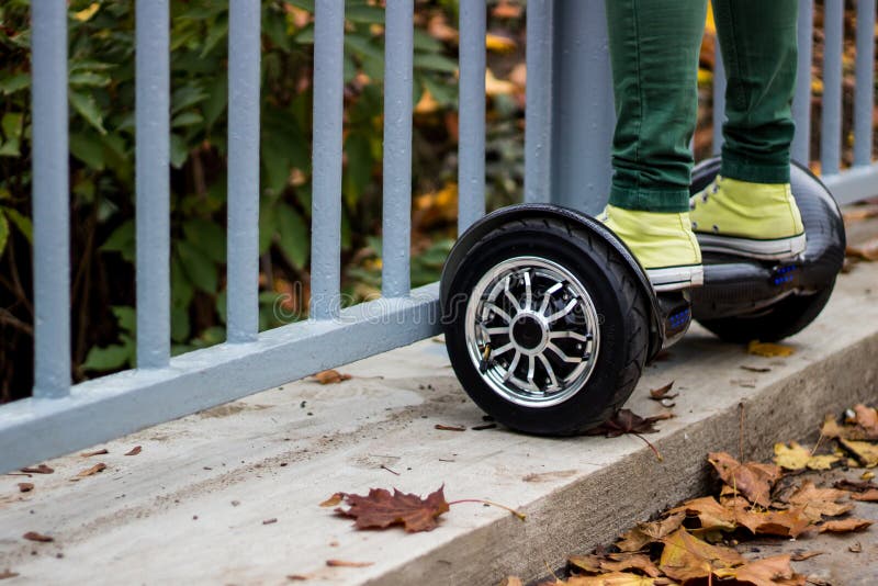 Equipaggi la condizione vicino al recinto sul hoverboard nero fotografie stock libere da diritti Equipaggi la condizione vicino al recinto sul hoverboard nero fotografie stock libere da diritti