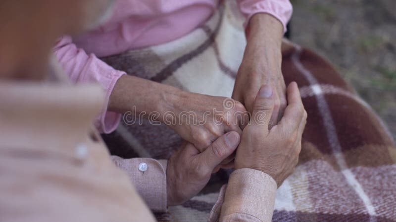 Equipaggi la tenuta le mani, l'amore della famiglia e della cura femminili vecchi, vecchie coppie nella casa di cura