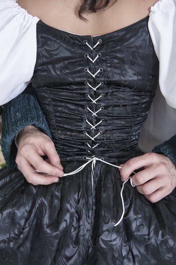 Equipaggi le mani che sciolgono il corsetto della donna in vestito medievale fotografia stock libera da diritti Equipaggi le mani che sciolgono il corsetto della donna in vestito medievale fotografia stock libera da diritti