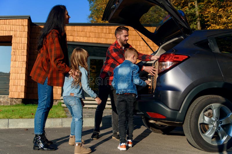 Equipaje de embalaje de la familia feliz en el maletero de un coche antes de pasar a una nueva casa o ir a las vacaciones. fotos de archivo