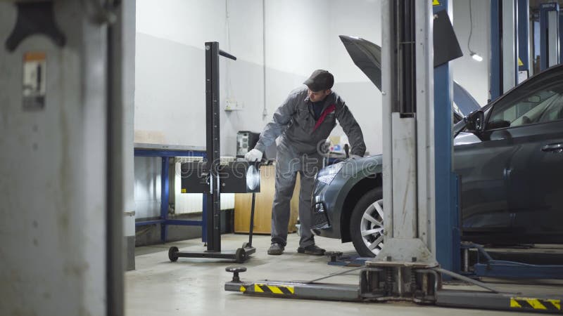 Equipamento de raios de ajuste automático para profissionais adultos na oficina de reparação automática. homem caucasiano apertand