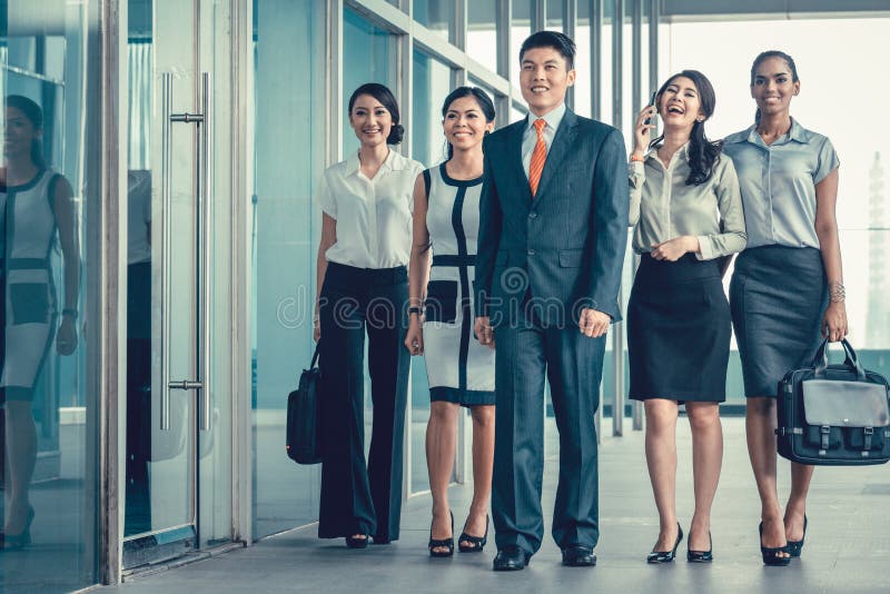 A equipe asiática do negócio dos executivos que andam no escritório intimida muito foto de stock A equipe asiática do negócio dos executivos que andam no escritório intimida muito foto de stock