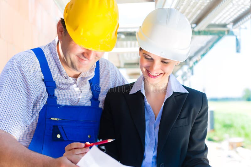Equipe da construção com planos da construção no local fotografia de stock