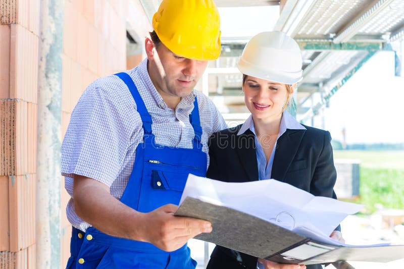 Equipa de construção com plantas do edifício no local foto de stock royalty free
