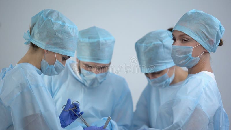 Equipe de cirurgiões que trabalha na sala de operações, enfermeiros verificando a taxa ecg no monitor