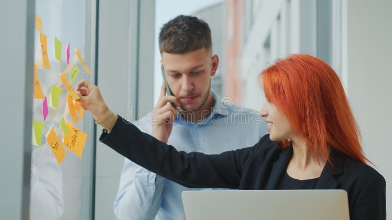 Equipe de dois jovens parceiros de negócios discutindo orientações estratégicas de negócios conversando ao telefone em um laptop