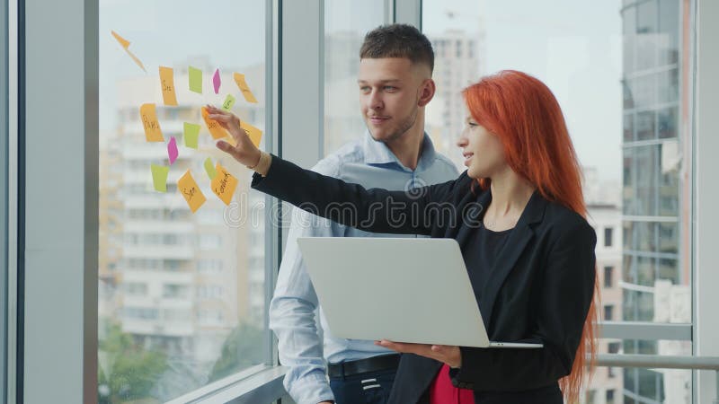 Equipe de dois jovens parceiros de negócios discutindo orientações estratégicas de negócios conversando ao telefone em um laptop