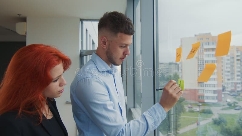 Equipe de dois jovens parceiros de negócios discutindo orientações estratégicas de negócios conversando ao telefone em um laptop