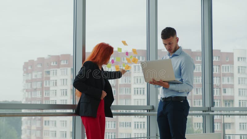 Equipe de dois jovens parceiros de negócios discutindo orientações estratégicas de negócios conversando ao telefone em um laptop