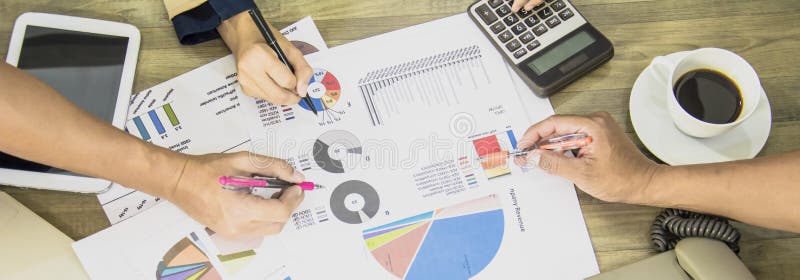 Businessman and Business women team analyze documents presentation shareholders meeting,charts and marketing plan graphs, on office`s wooden table,banner web horizontal for header. Businessman and Business women team analyze documents presentation shareholders meeting,charts and marketing plan graphs, on office`s wooden table,banner web horizontal for header