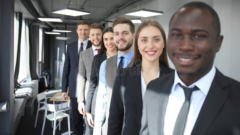 Equipe de sorriso feliz do negócio que está em seguido no escritório imagens de stock royalty free Equipe de sorriso feliz do negócio que está em seguido no escritório imagens de stock royalty free