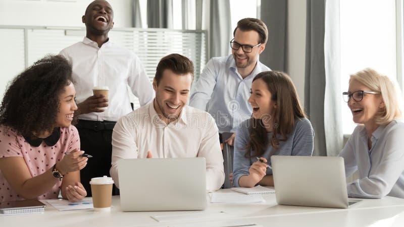 Equipe diversa feliz dos trabalhadores de escritório que ri junto na reunião de grupo