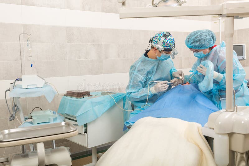 Equipe do dentista que trabalha com paciente Dentista na máscara com binóculos da lupa foto de stock Equipe do dentista que trabalha com paciente Dentista na máscara com binóculos da lupa foto de stock