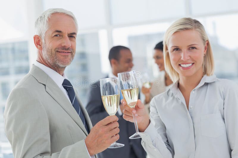Equipe do negócio que comemora com champanhe e que olha a câmera imagem de stock royalty free Equipe do negócio que comemora com champanhe e que olha a câmera imagem de stock royalty free
