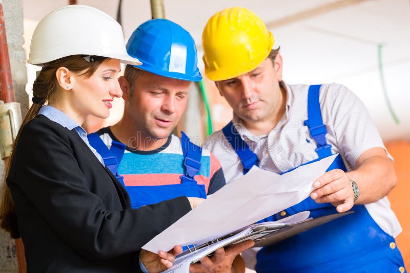 Equipa de trabalho num estaleiro de construção a controlar a planta baixa fotografia de stock
