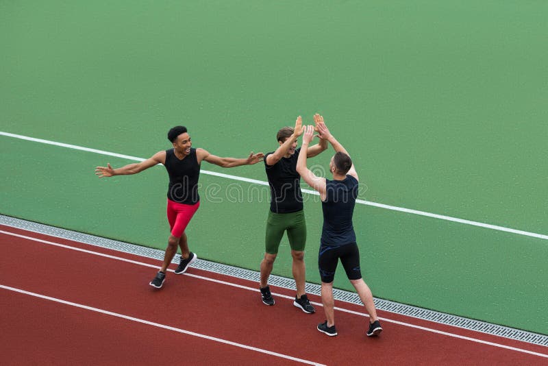 Equipe multi-étnico do atleta que está na pista de atletismo fotografia de stock Equipe multi-étnico do atleta que está na pista de atletismo fotografia de stock