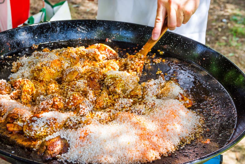 Equipe a mão do ` s que guarda Turner de madeira, misturando o arroz cru com as especiarias do molho de tomate da carne do frango imagens de stock royalty free Equipe a mão do ` s que guarda Turner de madeira, misturando o arroz cru com as especiarias do molho de tomate da carne do frango imagens de stock royalty free