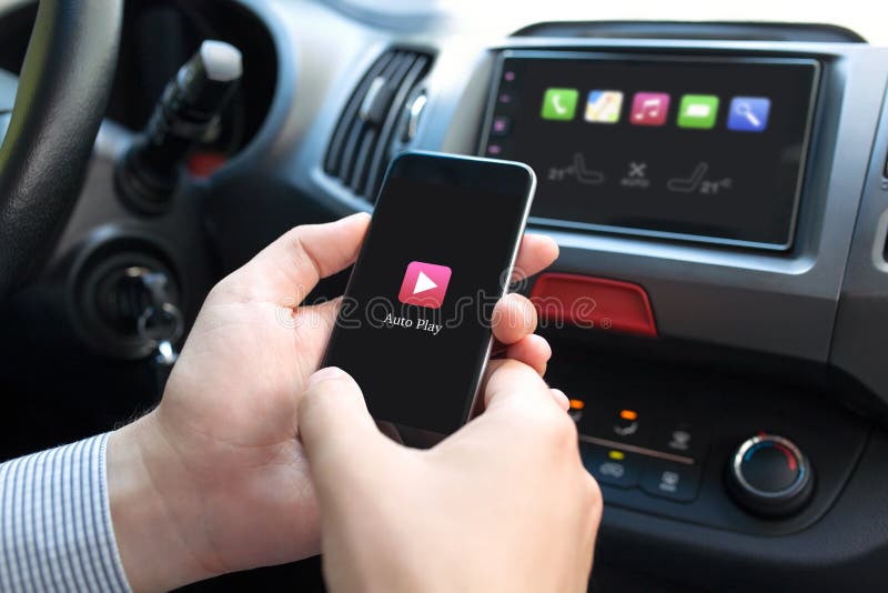 Man hand in car holding phone with app Auto Play on the screen and on multimedia system. Man hand in car holding phone with app Auto Play on the screen and on multimedia system