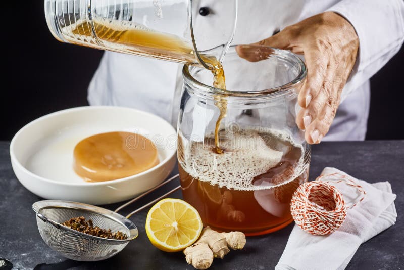 Man pouring filtered kombucha SCOBY tea into jar. Man pouring filtered kombucha SCOBY tea into jar