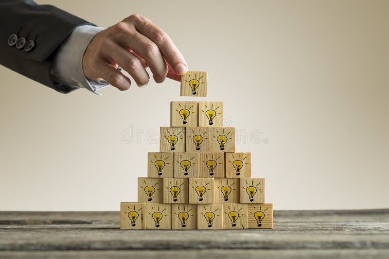 Equipe o empilhamento de uma torre com as ampolas amarelas numa forma de um pyra imagem de stock Equipe o empilhamento de uma torre com as ampolas amarelas numa forma de um pyra imagem de stock