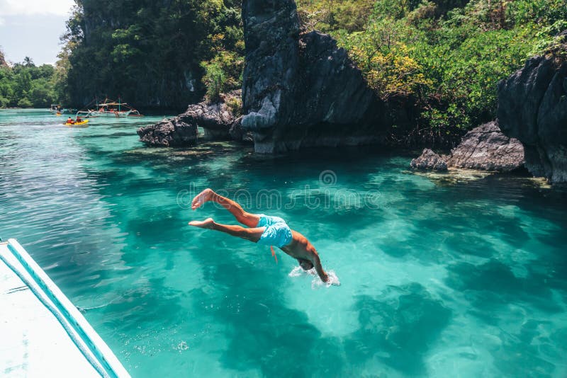 Man jumping into clear sea water in lagoon. Travelling tour in Asia: El Nido, Palawan, Philippines. Man jumping into clear sea water in lagoon. Travelling tour in Asia: El Nido, Palawan, Philippines.