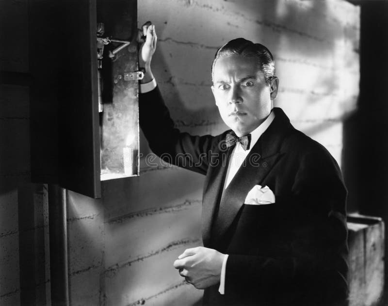 Man standing in front of a fuse box looking frightened (All persons depicted are no longer living and no estate exists. Supplier grants that there will be no model release issues.). Man standing in front of a fuse box looking frightened (All persons depicted are no longer living and no estate exists. Supplier grants that there will be no model release issues.)