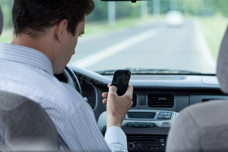 Equipe texting no telefone celular durante a condução de um carro fotografia de stock Equipe texting no telefone celular durante a condução de um carro fotografia de stock