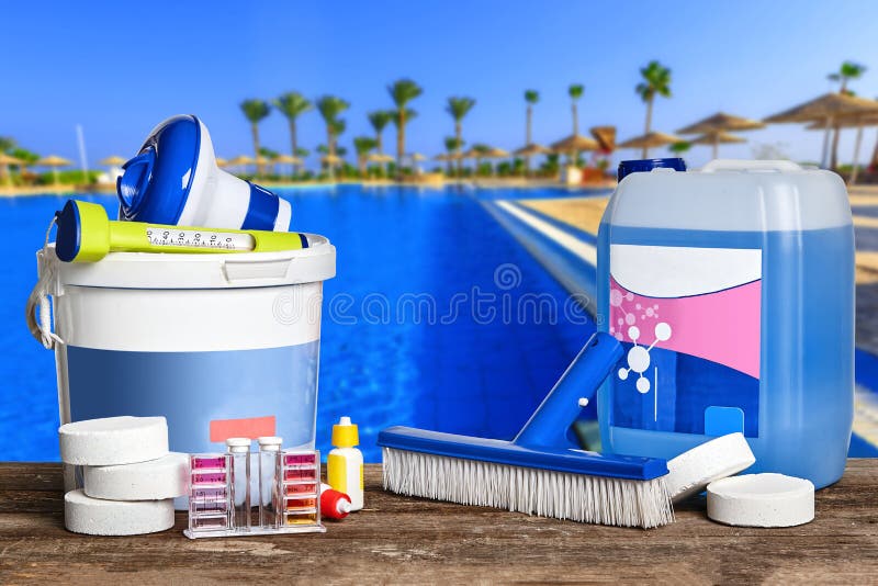 New equipment with chemical cleaning products and tools for the maintenance of the swimming pool on wooden surface against a nature background. Horizontal composition. Close-up front view. New equipment with chemical cleaning products and tools for the maintenance of the swimming pool on wooden surface against a nature background. Horizontal composition. Close-up front view.