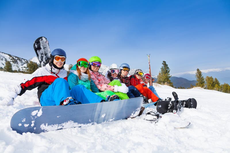 Equipo con las snowboard y las gafas que se sientan en fila imagenes de archivo