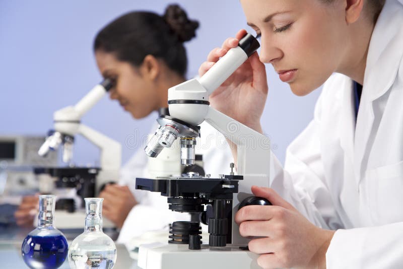 Equipo de investigación científica femenino usando los microscopios