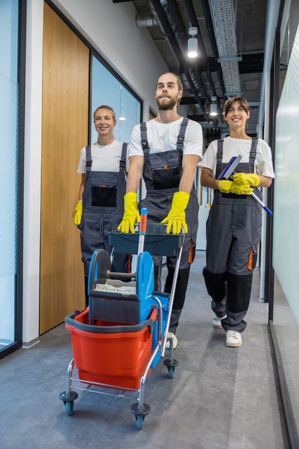 Equipo de limpieza caminando por el pasillo de la oficina con equipo de limpieza imagen de archivo libre de regalías