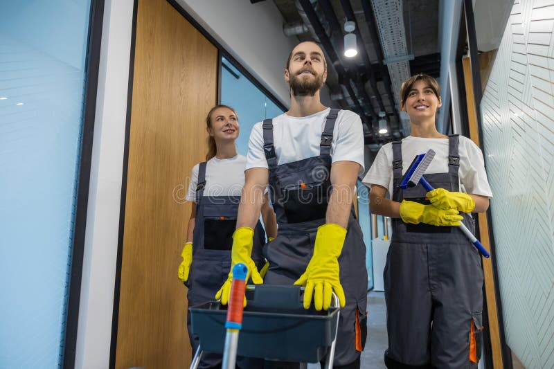 Equipo de limpieza caminando por el pasillo de la oficina con equipo de limpieza imagen de archivo