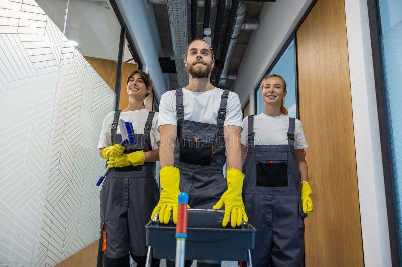 Equipo de limpieza caminando por el pasillo de la oficina con equipo de limpieza imagen de archivo libre de regalías