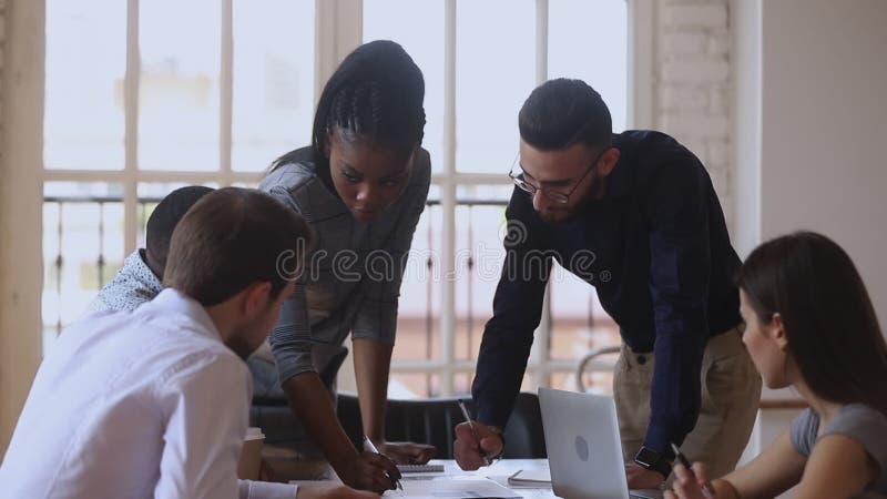 Equipo de negocios diverso enfocado discute el papeleo en la reunión de información metrajes