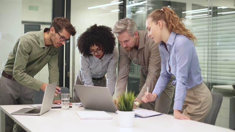 Equipo de negocios de inicio en reunión en el moderno y brillante interior de oficina y trabajando en laptop almacen de video