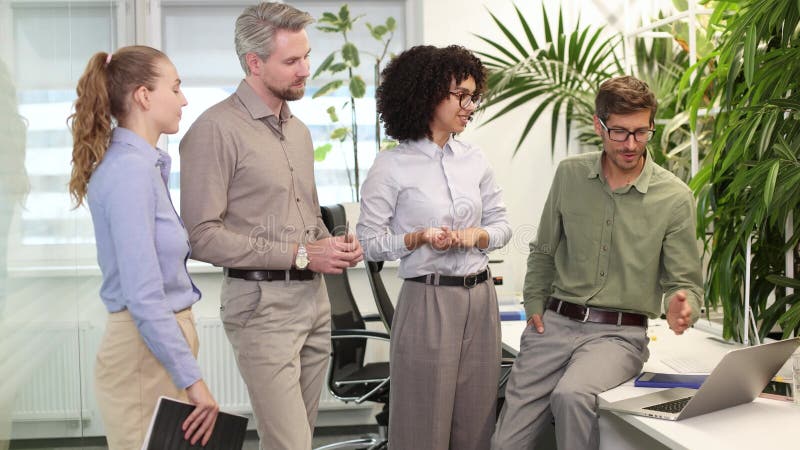 Equipo de negocios de inicio en reunión en el moderno y brillante interior de oficina y trabajando en laptop almacen de metraje de vídeo