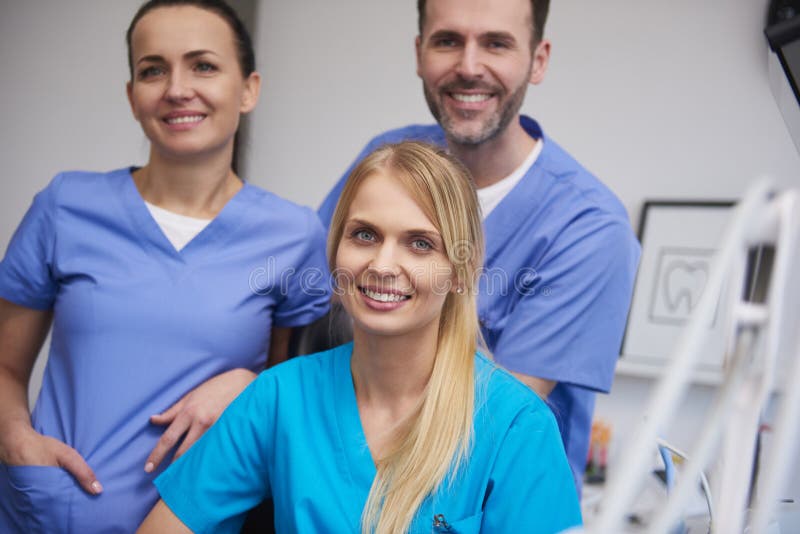 Team of smiling and satisfied dentists in medical uniform in dentist`s office. Team of smiling and satisfied dentists in medical uniform in dentist`s office