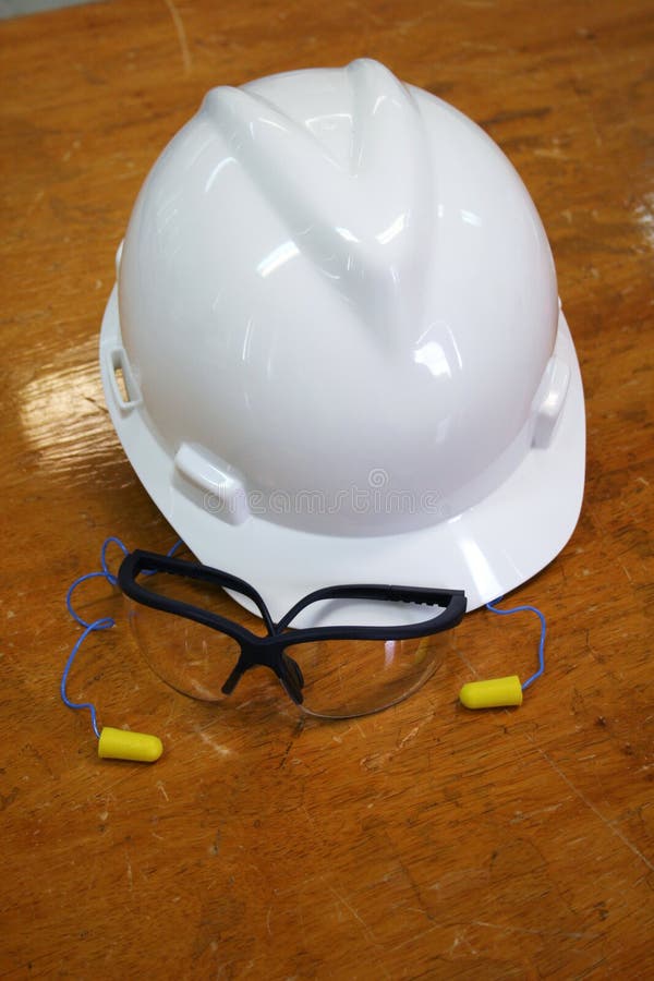 Hardhat, clear safety goggles and earplugs on a table. Hardhat, clear safety goggles and earplugs on a table