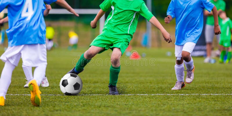 Youth soccer football teams kicking soccer ball on a sports pitch. Soccer tournament for young footballers. Youth soccer football teams kicking soccer ball on a sports pitch. Soccer tournament for young footballers.