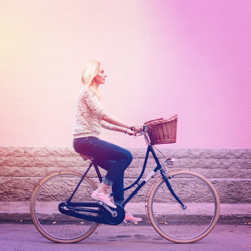Equitação da mulher na bicicleta do vintage com cesta fotos de stock royalty free Equitação da mulher na bicicleta do vintage com cesta fotos de stock royalty free
