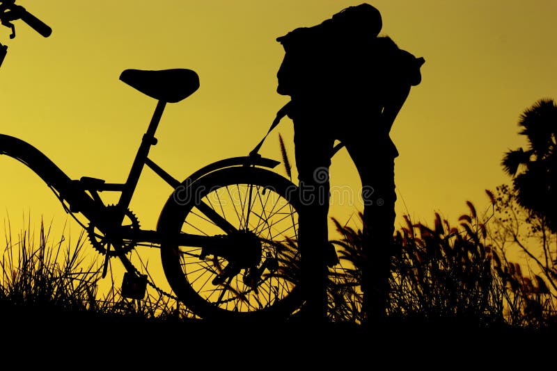 A equitação do rapaz pequeno e da menina bikes no por do sol, crianças ativas ostenta, criança asiática, mostra em silhueta uma c imagem de stock A equitação do rapaz pequeno e da menina bikes no por do sol, crianças ativas ostenta, criança asiática, mostra em silhueta uma c imagem de stock