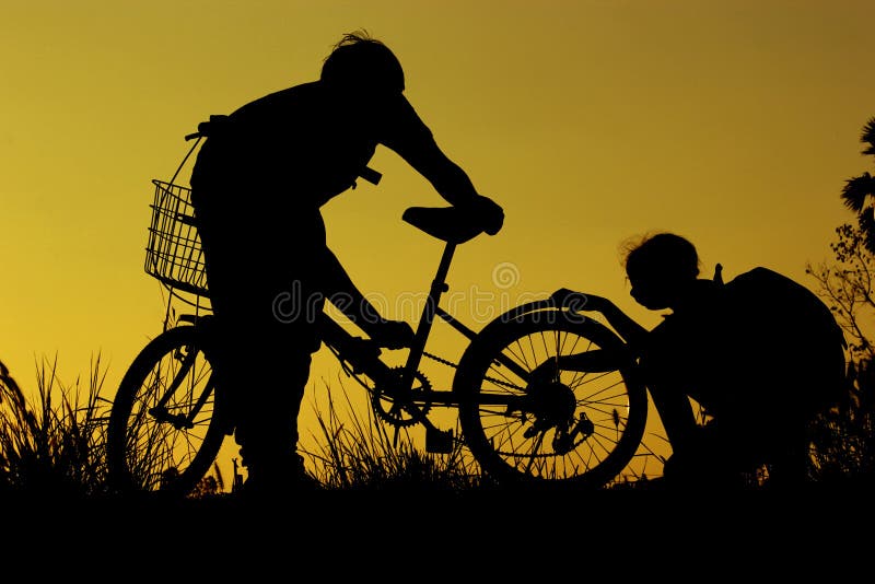 A equitação do rapaz pequeno e da menina bikes no por do sol, crianças ativas ostenta, criança asiática, mostra em silhueta uma c foto de stock royalty free A equitação do rapaz pequeno e da menina bikes no por do sol, crianças ativas ostenta, criança asiática, mostra em silhueta uma c foto de stock royalty free