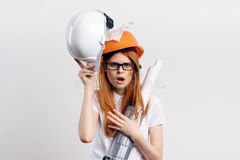 Erbauerfrau in einem orange Sturzhelm auf einem grauen Hintergrund stockbild Erbauerfrau in einem orange Sturzhelm auf einem grauen Hintergrund stockbild