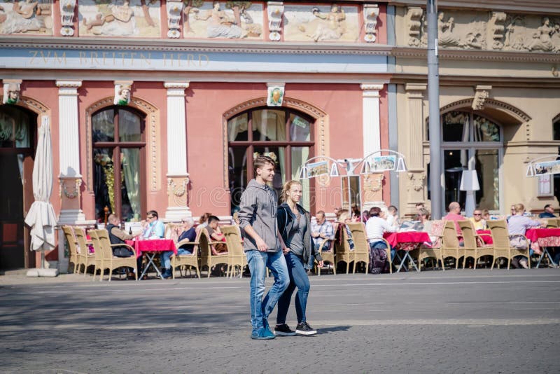 Erfurt, Germania 7 aprile 2019 Giovani coppie romantiche che tengono mano e che camminano nel centro urbano fotografia stock Erfurt, Germania 7 aprile 2019 Giovani coppie romantiche che tengono mano e che camminano nel centro urbano fotografia stock