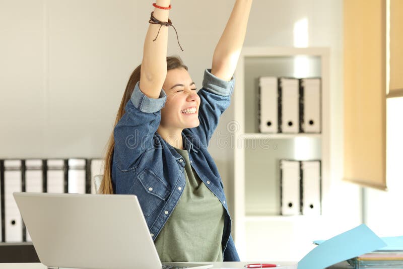 Portrait of a young satisfied intern raising arms at office. Portrait of a young satisfied intern raising arms at office